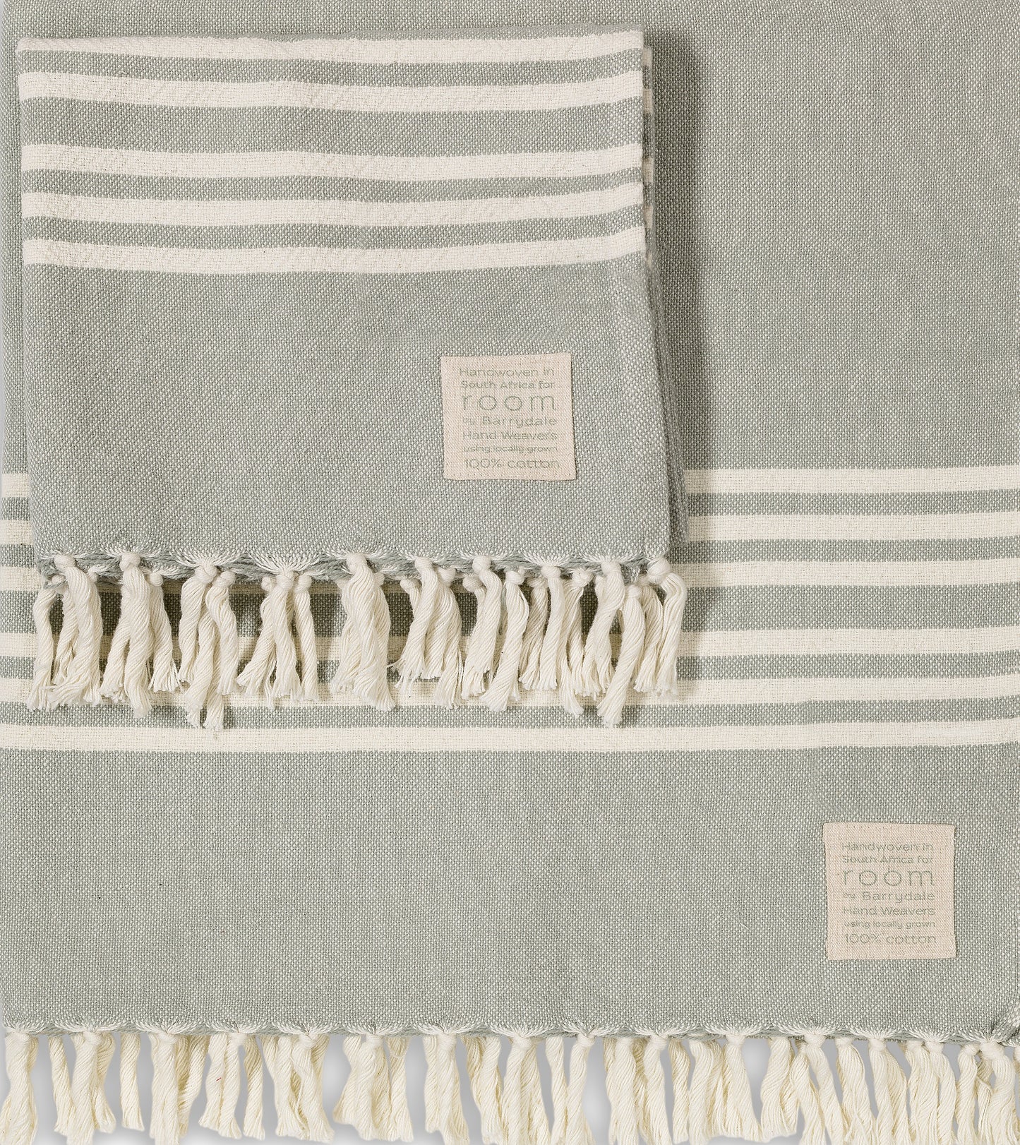 The Barrydale Hand Weavers' 100% Cotton Hand Towel in The Room Key's green and grey is a handwoven textile crafted from 100% locally sourced, unbleached cotton. Measuring approximately 85cm in width and 160cm in length, this towel offers ample coverage for various uses.
