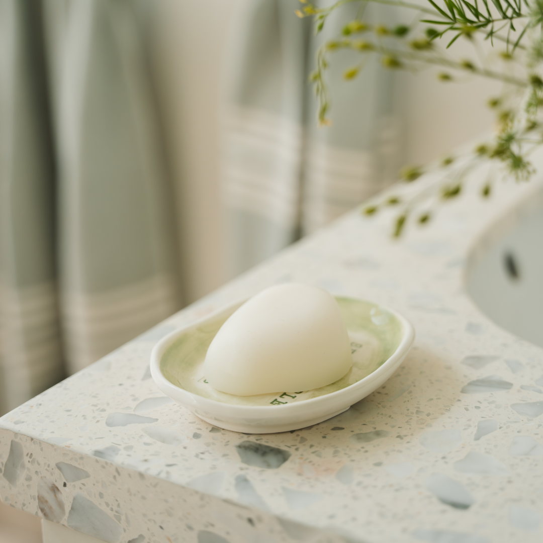 Pebble-shaped natural soap resting in a minimalist soap dish. Infused with pure essential oils like Neroli, Vetiver, and Lemon Verbena, the soap lathers richly while moisturizing the skin. A luxurious, SLS-, paraben-, and palm oil–free blend with a perfume-like scent.